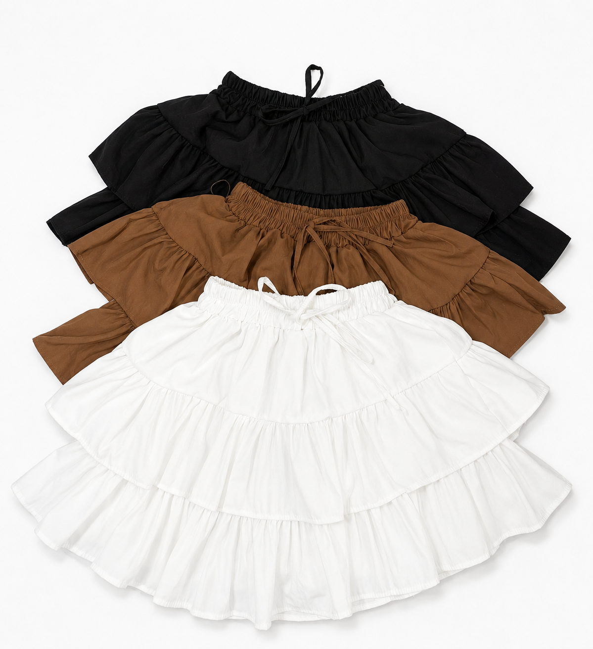 Three tiered ruffled skirts in black, brown, and white, arranged diagonally on a clean white background.